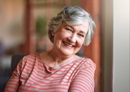 Older woman leaning on wall and smiling